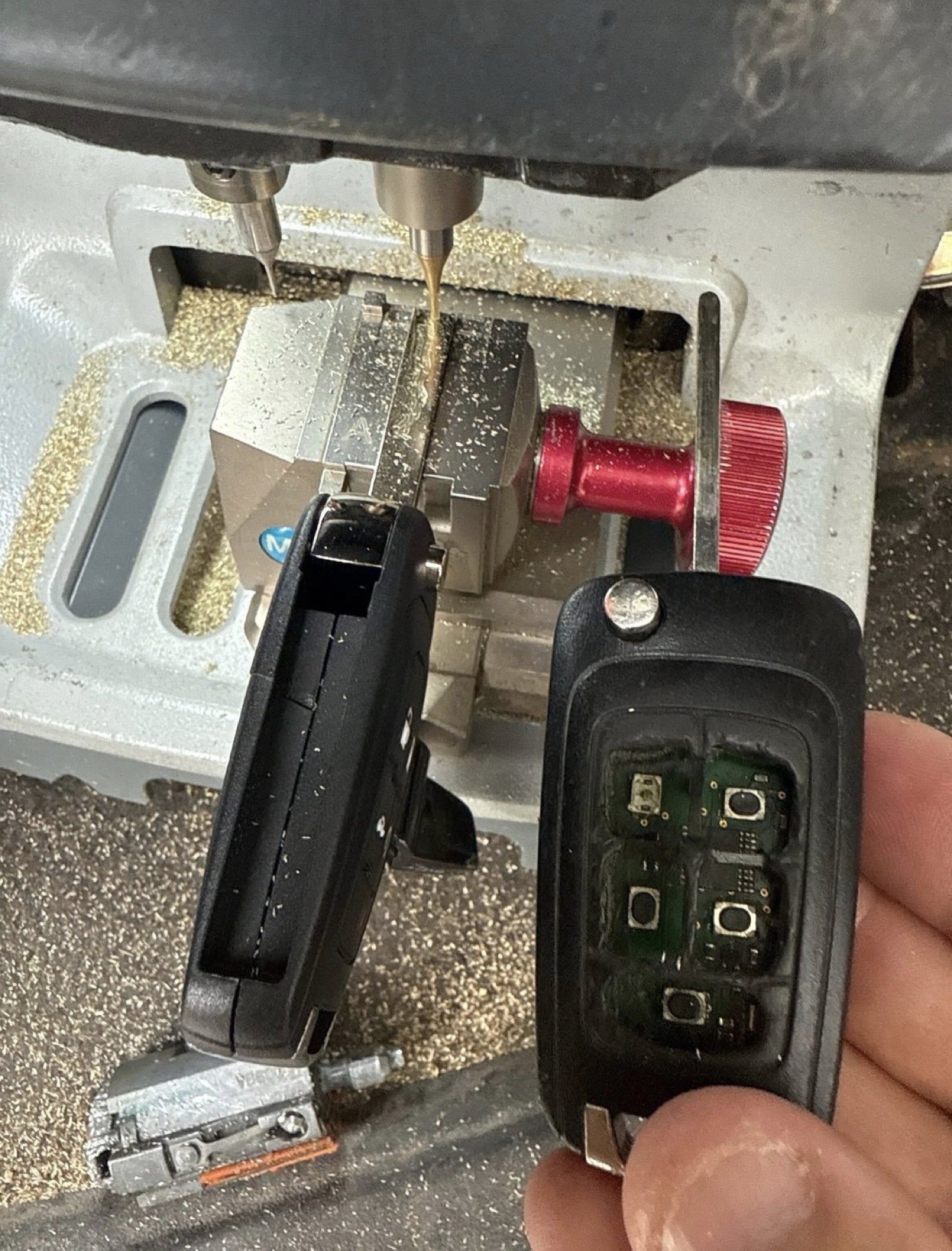 Chevrolet flip key being cut next to a damaged original, by City Locksmith Taylor