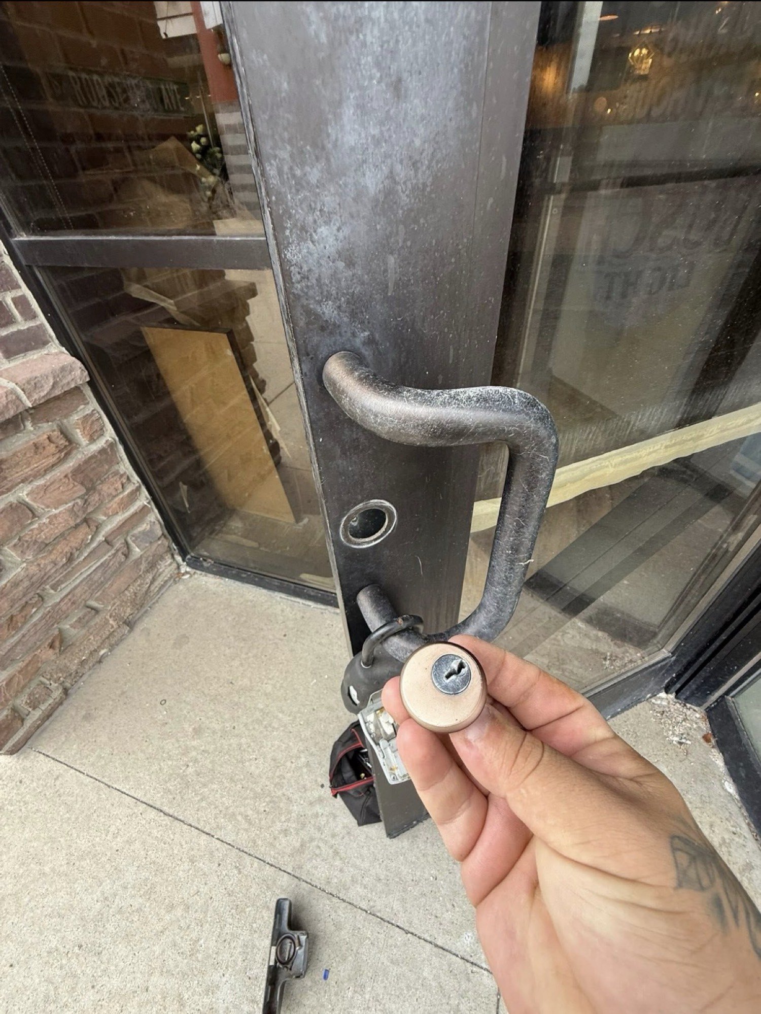 Mortise cylinder held at a commercial door during locksmith work